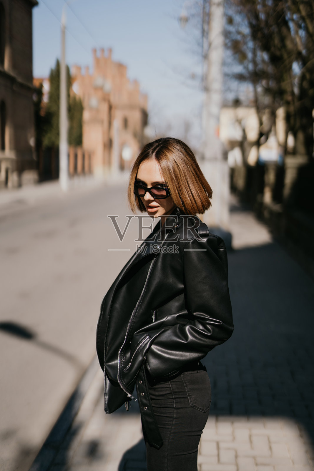 年轻时尚的女子穿着时尚的服装走在街上，穿着黑色的皮夹克，春秋季的风格，摆姿势，高皮靴照片摄影图片