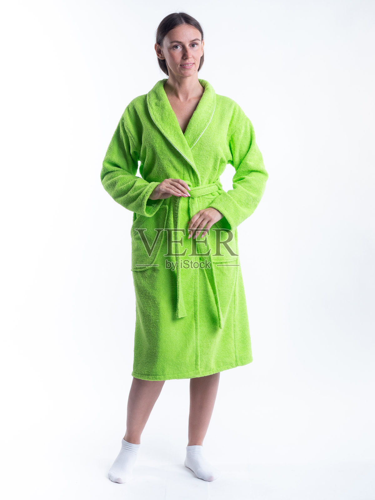 一个穿着浴袍的女人，站在一个孤立的白色背景下，脸上挂着微笑。照片摄影图片