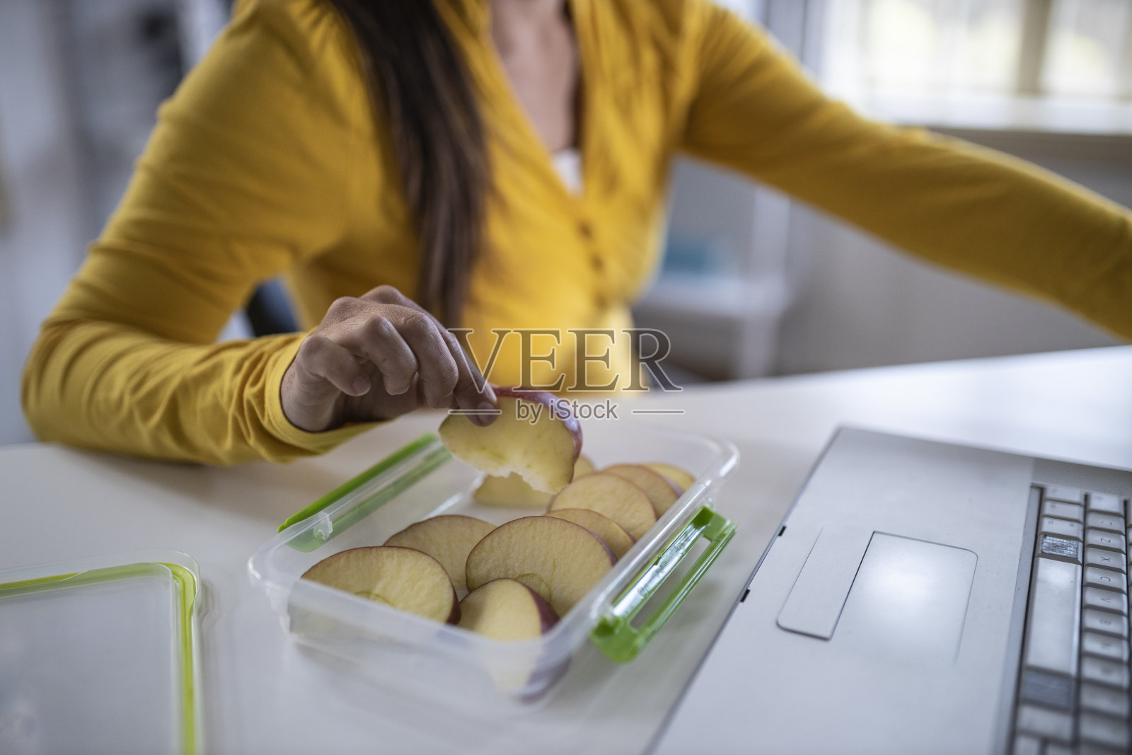 一名年轻女子一边在办公室独自工作，一边和朋友吃饭、开会。照片摄影图片