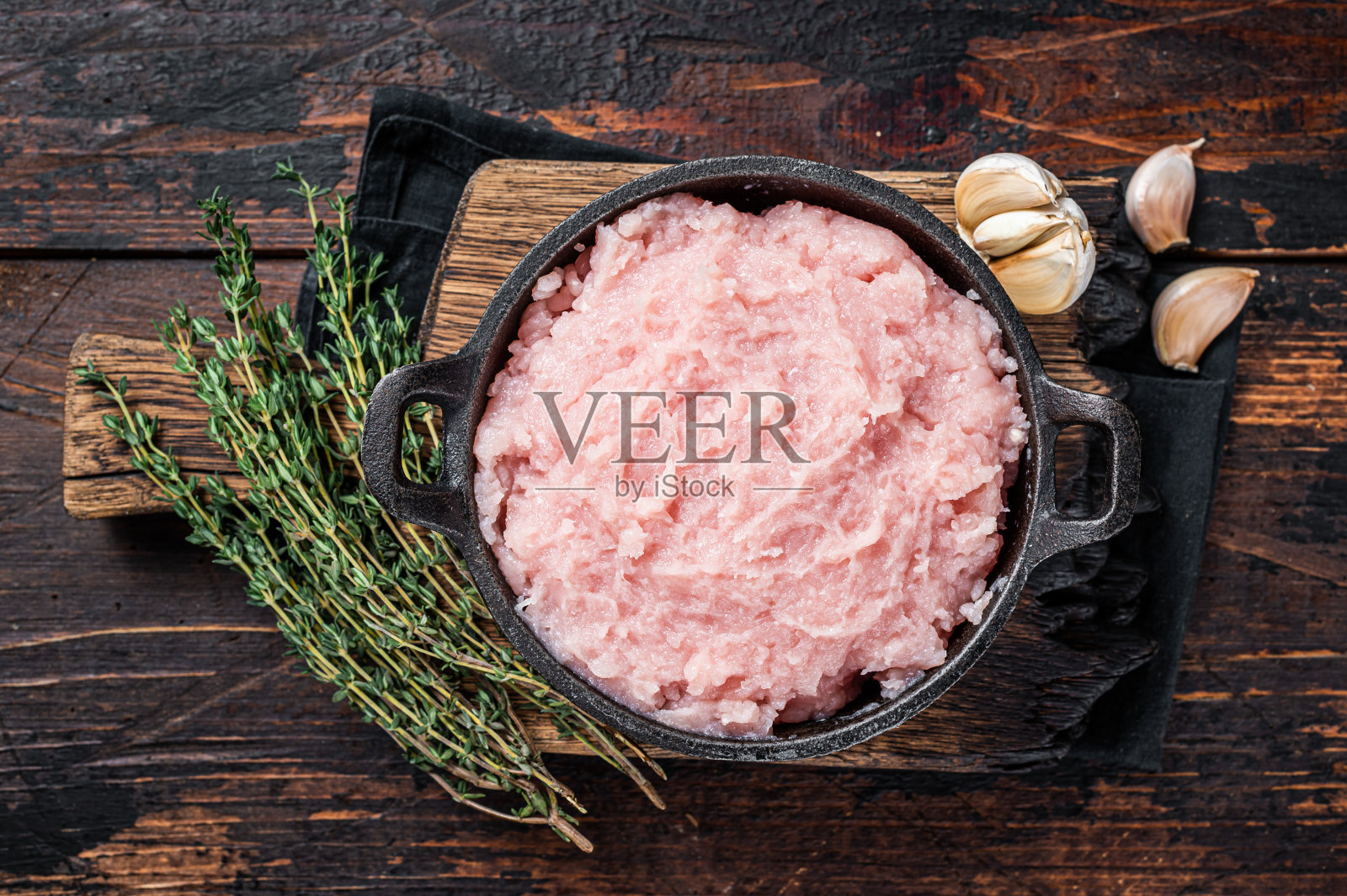 生切碎的鸡肉和火鸡肉，在平底锅里放上香草。深色木制背景。俯视图照片摄影图片