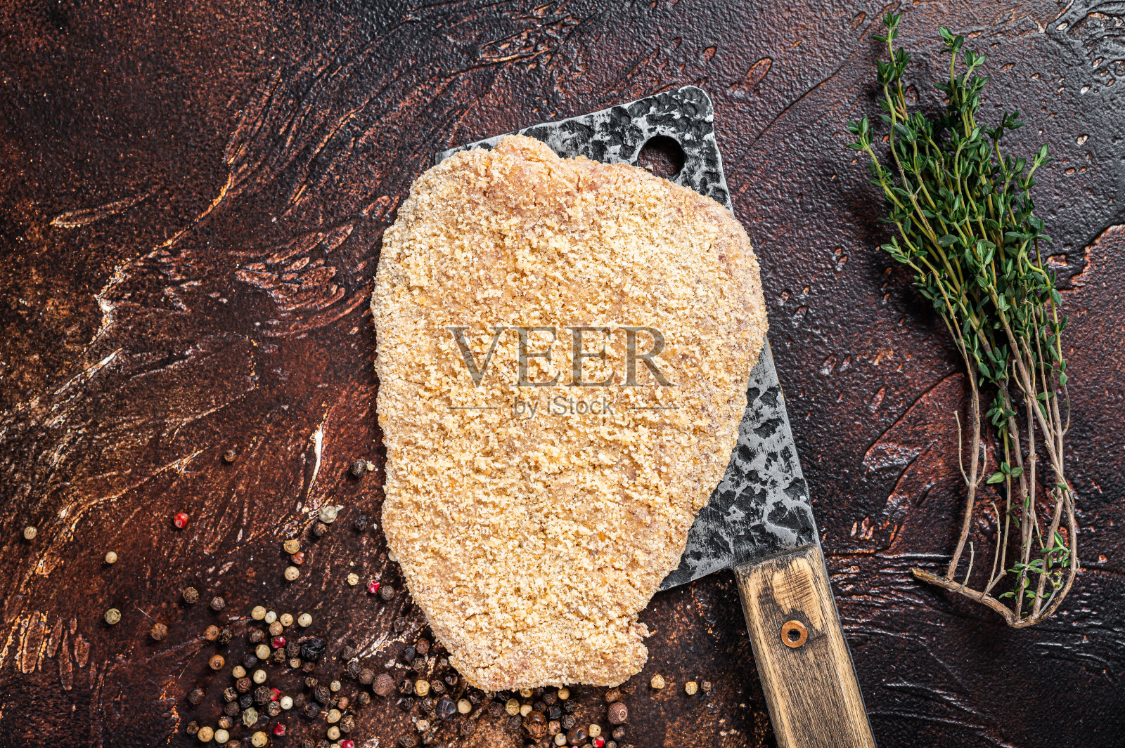 生肉排或炸肉排放在切肉刀上，配上香草。黑暗的背景。俯视图照片摄影图片