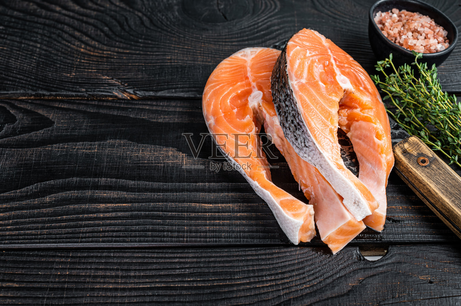 新鲜的生三文鱼牛排屠夫。黑色木制背景。前视图。本空间照片摄影图片