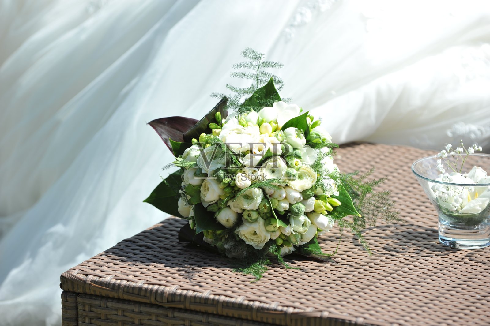 新娘的花束放在桌子上，靠近结婚戒指。照片摄影图片