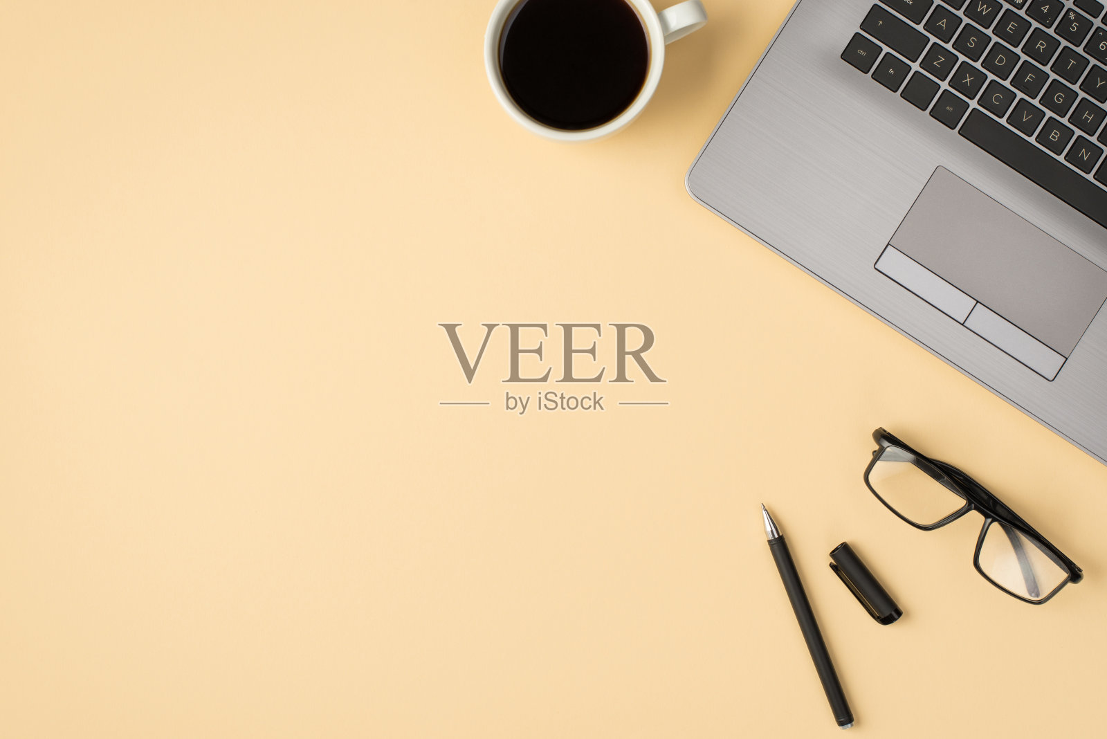 头顶照片的笔记本电脑眼镜，咖啡杯和笔孤立的米色背景与copyspace照片摄影图片