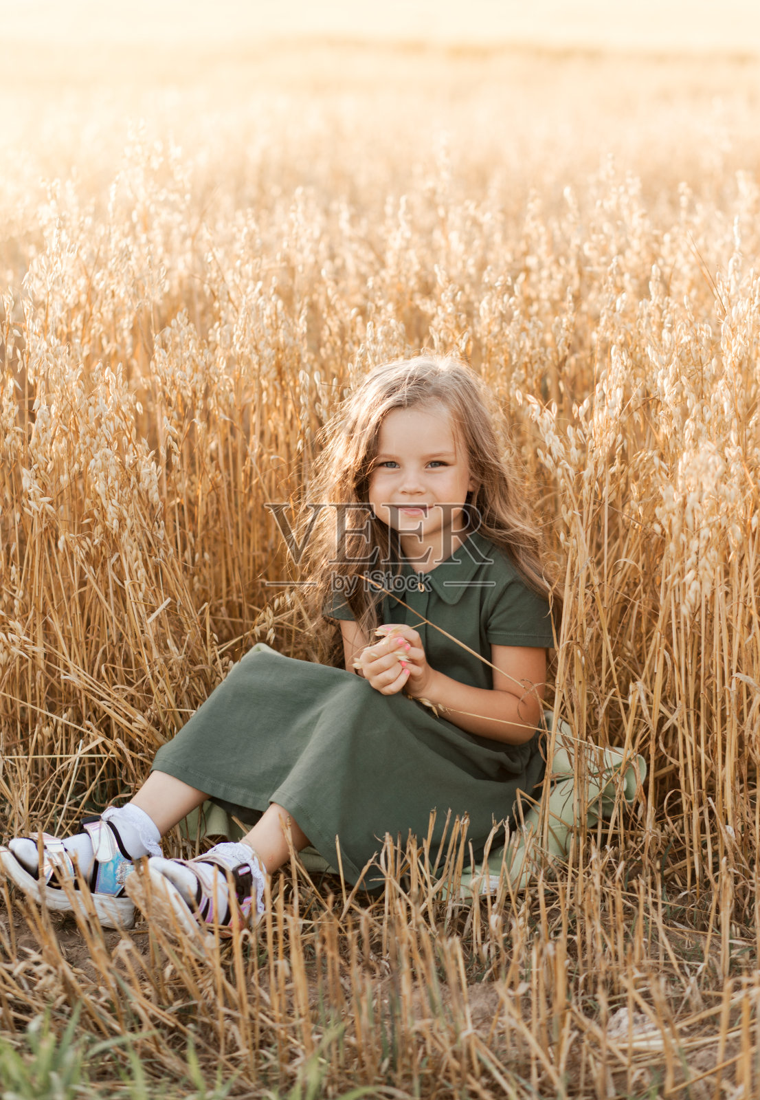 一个美丽的长发小女孩在阳光明媚的日子走过麦田。在户外肖像。孩子们放松照片摄影图片