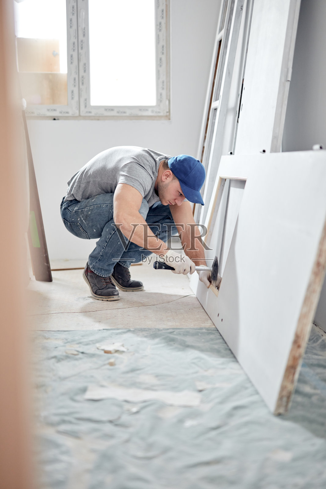 年轻的成年男子在DIY预算装修他的新家公寓。照片摄影图片