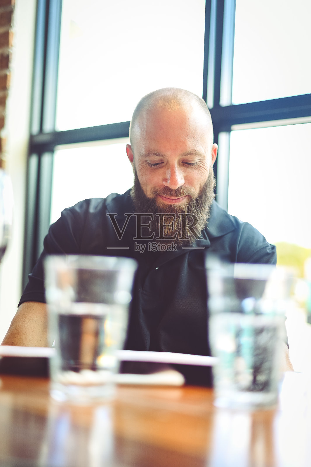 在餐厅里阅读菜单的络腮胡男人照片摄影图片