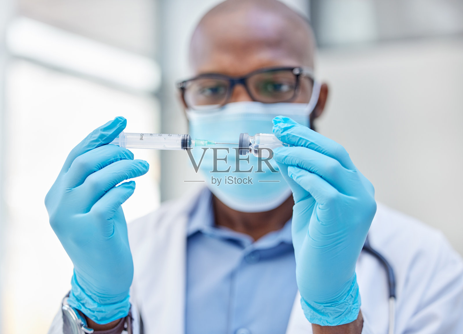 一名年轻医生用注射器从小瓶中取出药物照片摄影图片