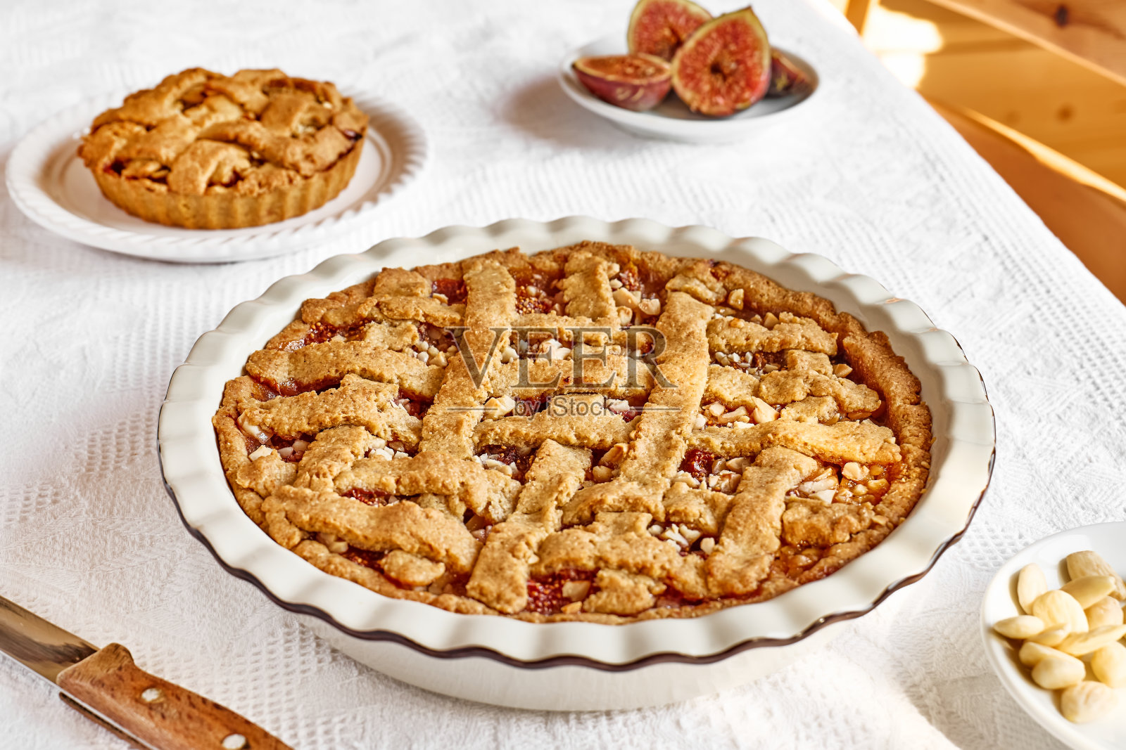 自制无花果挞配曲奇饼皮。铺着白色桌布的桌子上放着无花果和杏仁酥饼。秋天的烘烤。照片摄影图片