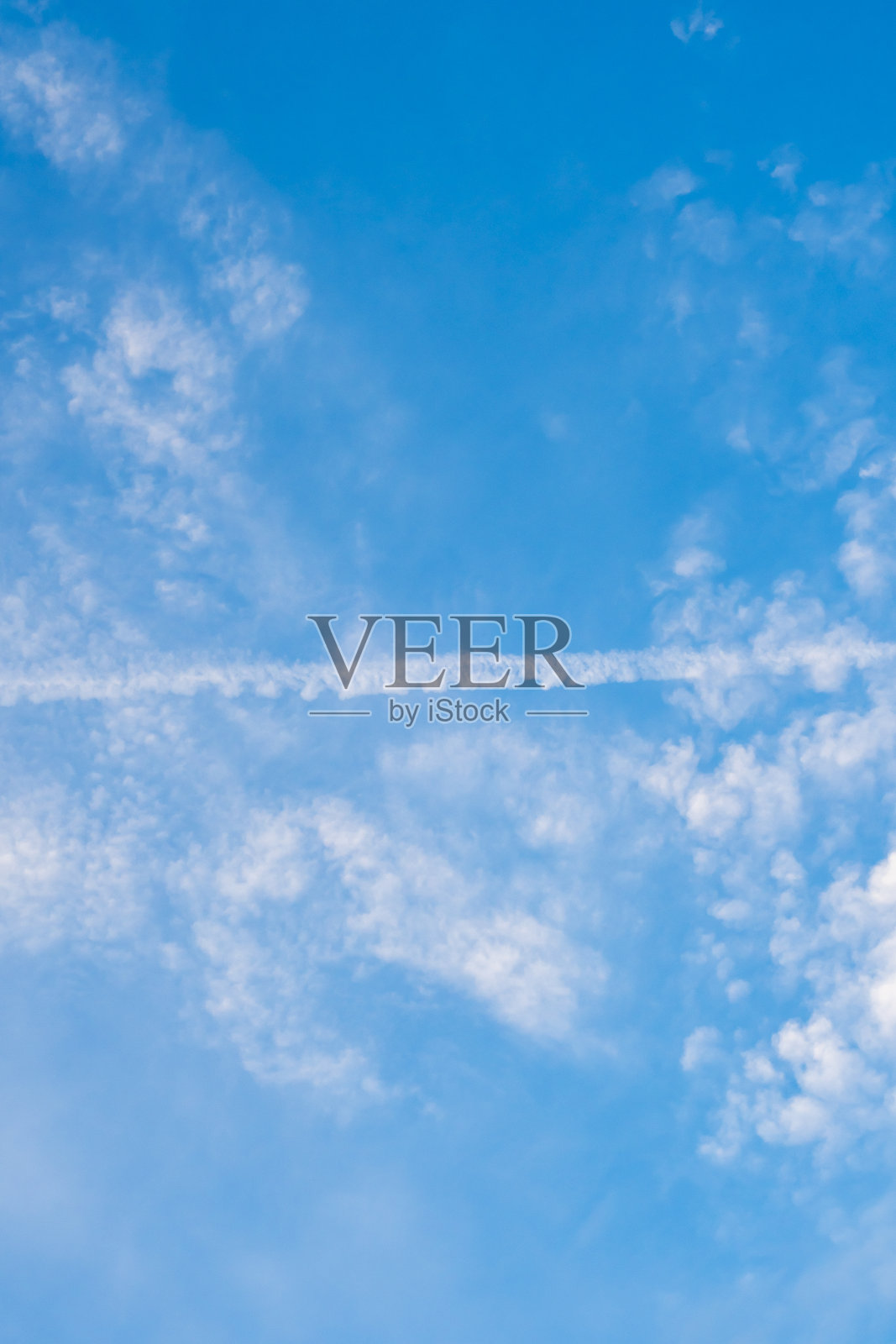 垂直模板上以航空或旅游为主题，用飞机的轨迹将天空分成两部分。蓝色的云层背景和飞机上的条纹作为封面或幻灯片照片摄影图片