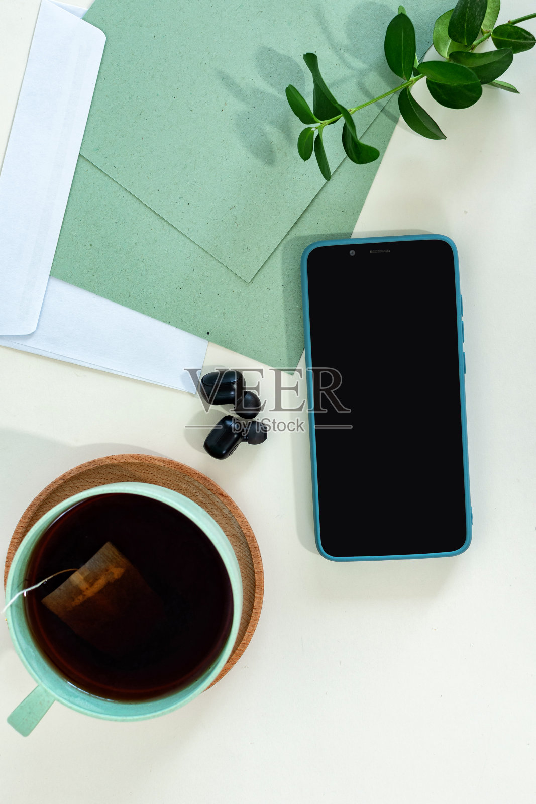 时尚男士在绿色现代办公桌上的智能手机、名片和茶杯特写照片摄影图片