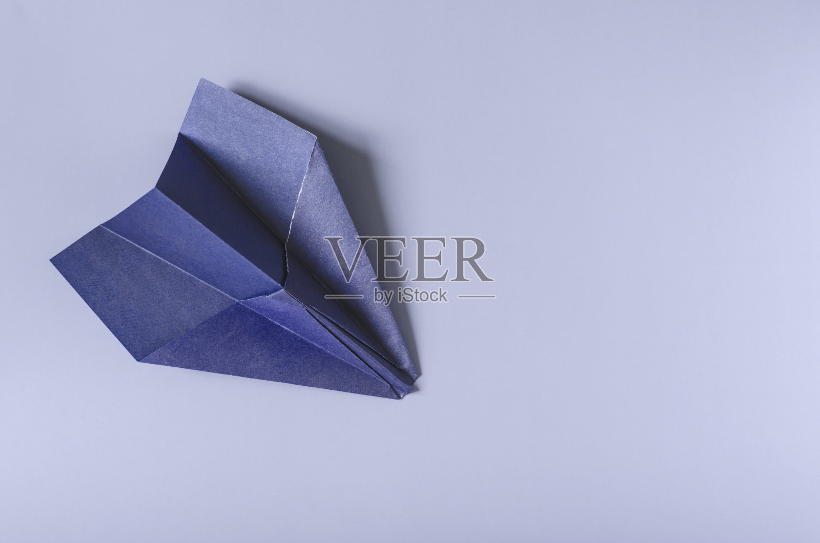 蓝色的纸飞机在彩色背景上。折纸用亮蓝色纸在彩色背景上复制飞机照片摄影图片