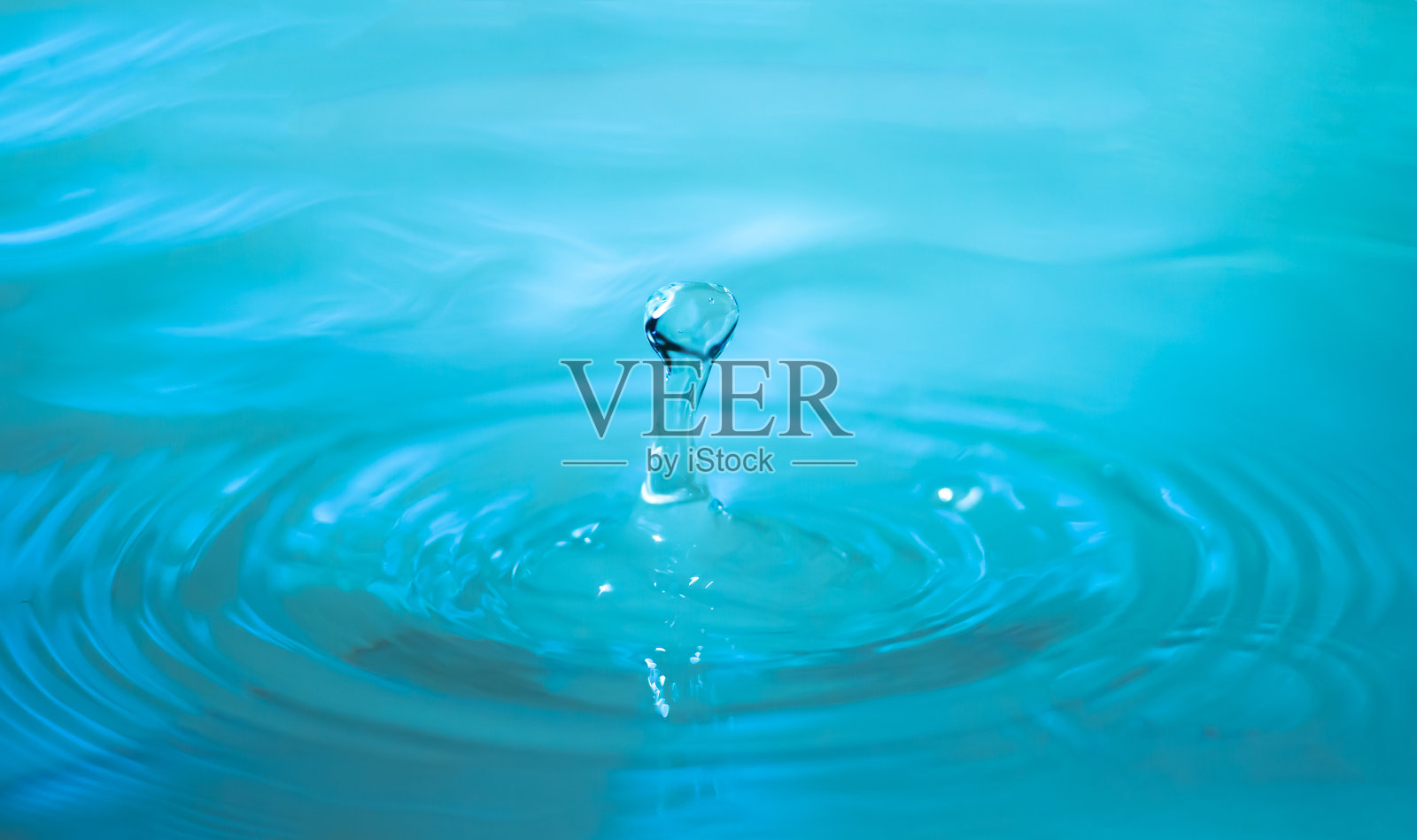 特写镜头中一滴蓝色的水落在水漏斗的漩涡上。背景照片摄影图片