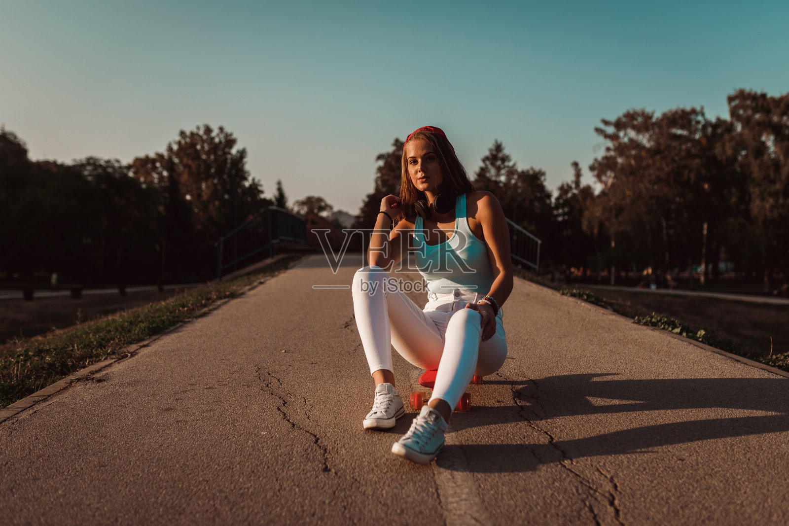 十几岁的女孩坐在城市公园的滑板上照片摄影图片