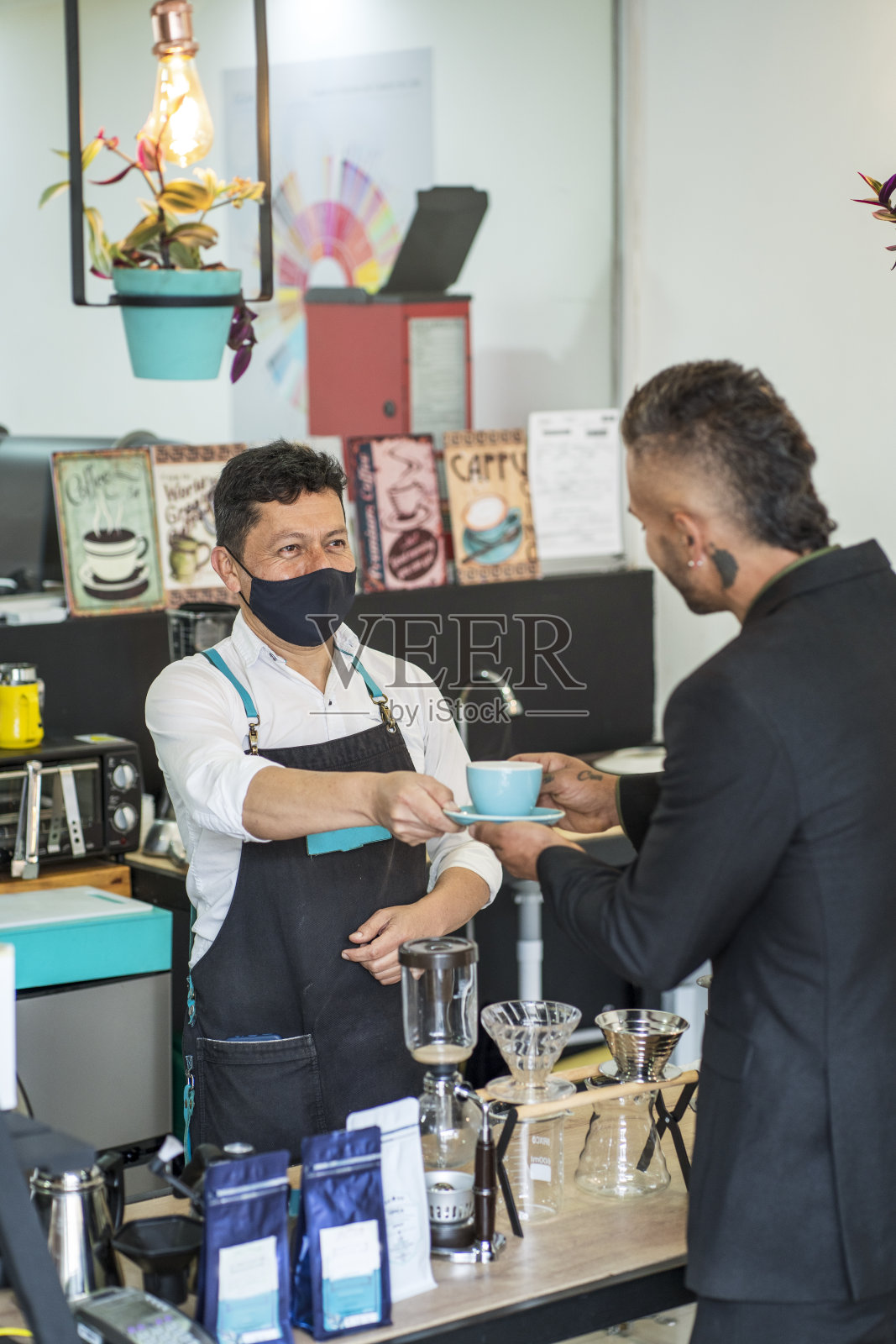 一家咖啡工厂的拉丁裔雇员站在为顾客准备咖啡的酒吧里照片摄影图片