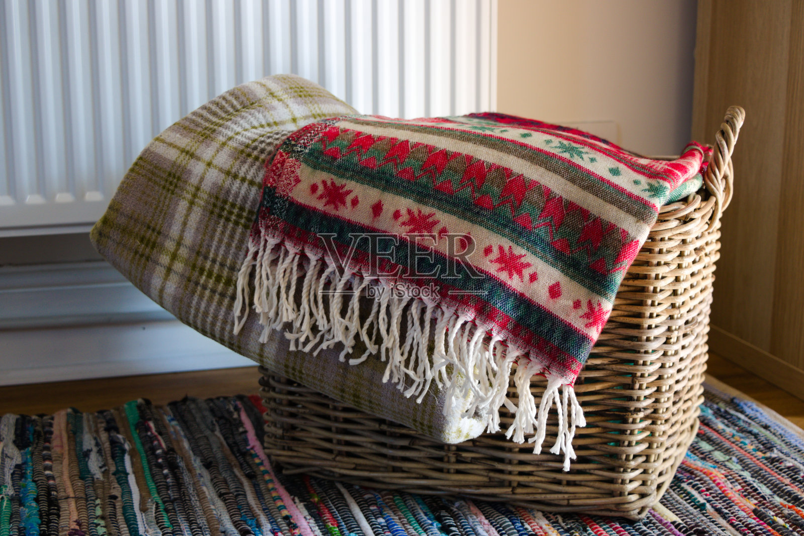 暖气片前面的柳条篮子里有暖和的毯子照片摄影图片