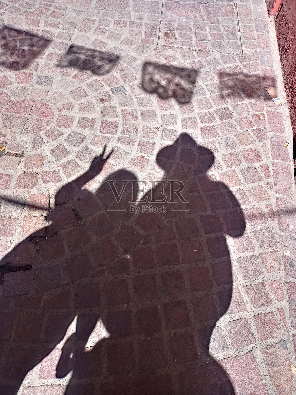 妈妈和女儿的影子在阳光下走在街道上，鹅卵石街道上可以看到街道宣政纸的影子照片摄影图片