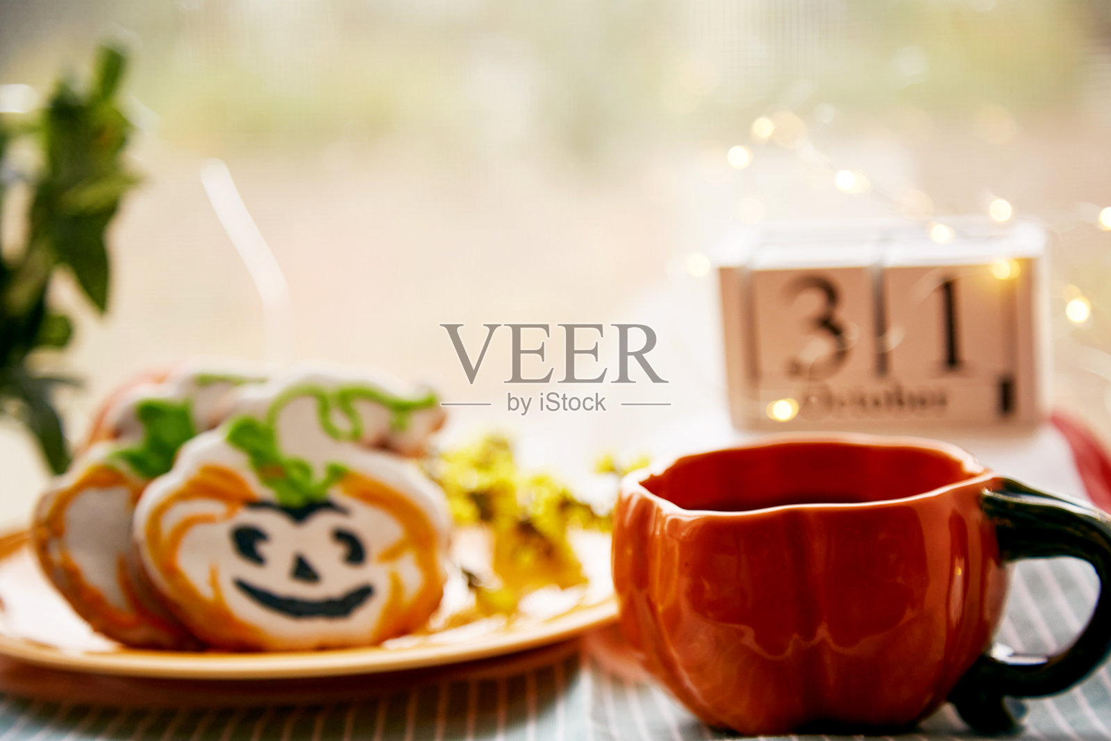 快乐的万圣节静物南瓜杯和自制的可爱的南瓜形状的饼干和万圣节的日期。大气美学的秋季假日概念。乡村生活照片摄影图片