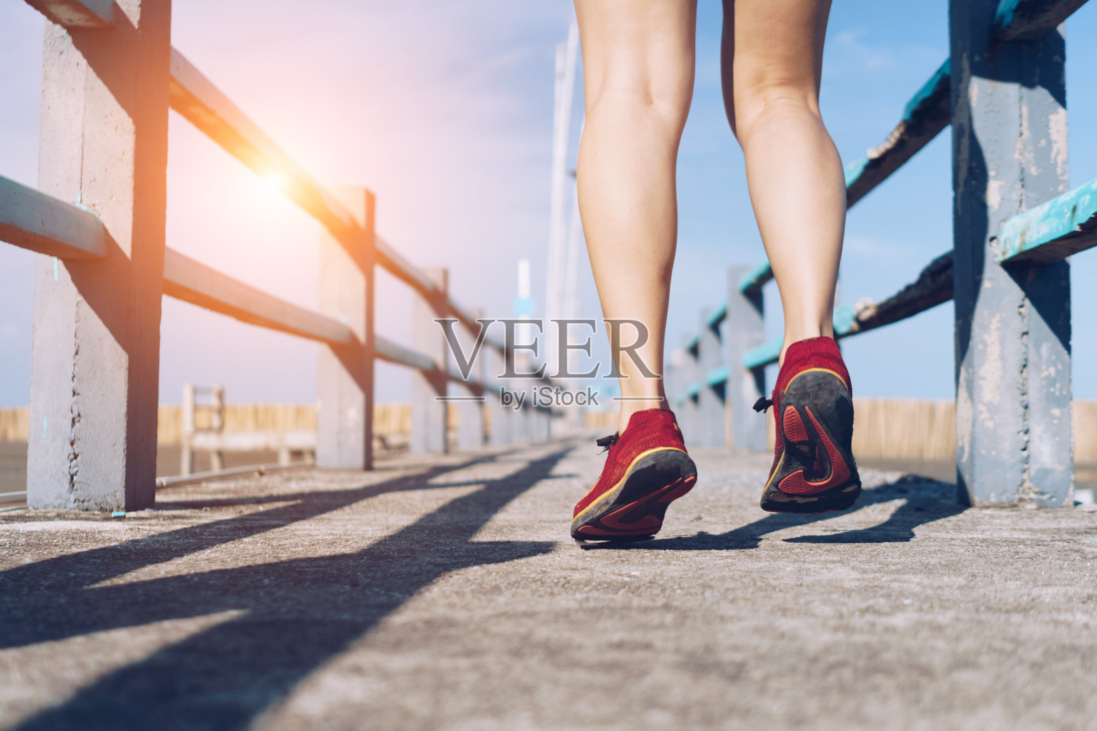 在绿色背景上，一名女子穿着跑鞋走路和跑步。锻炼是一种观念。照片摄影图片