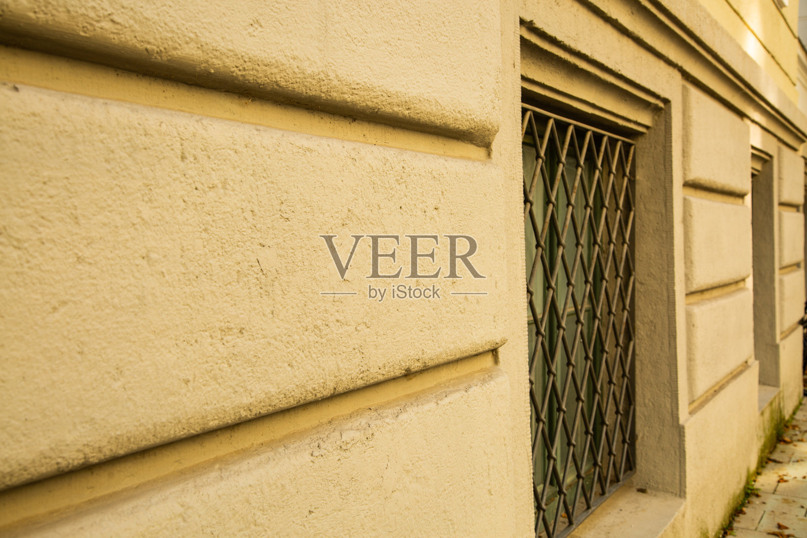 旧的地下室窗户，前面有栏杆，绿色的窗户，米色的房子外墙照片摄影图片