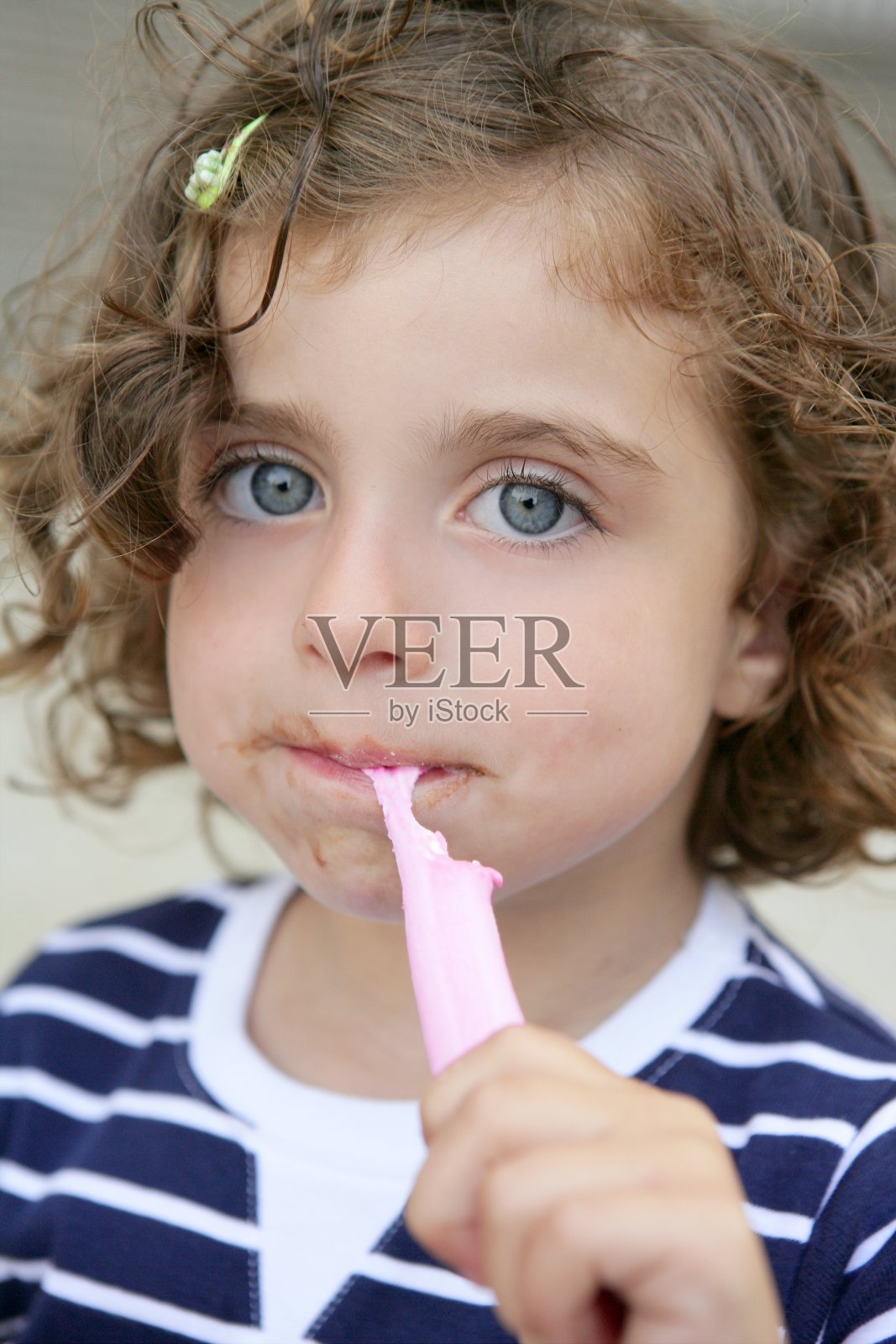 小女孩吃着甜甜的糖果，脏兮兮的脸照片摄影图片