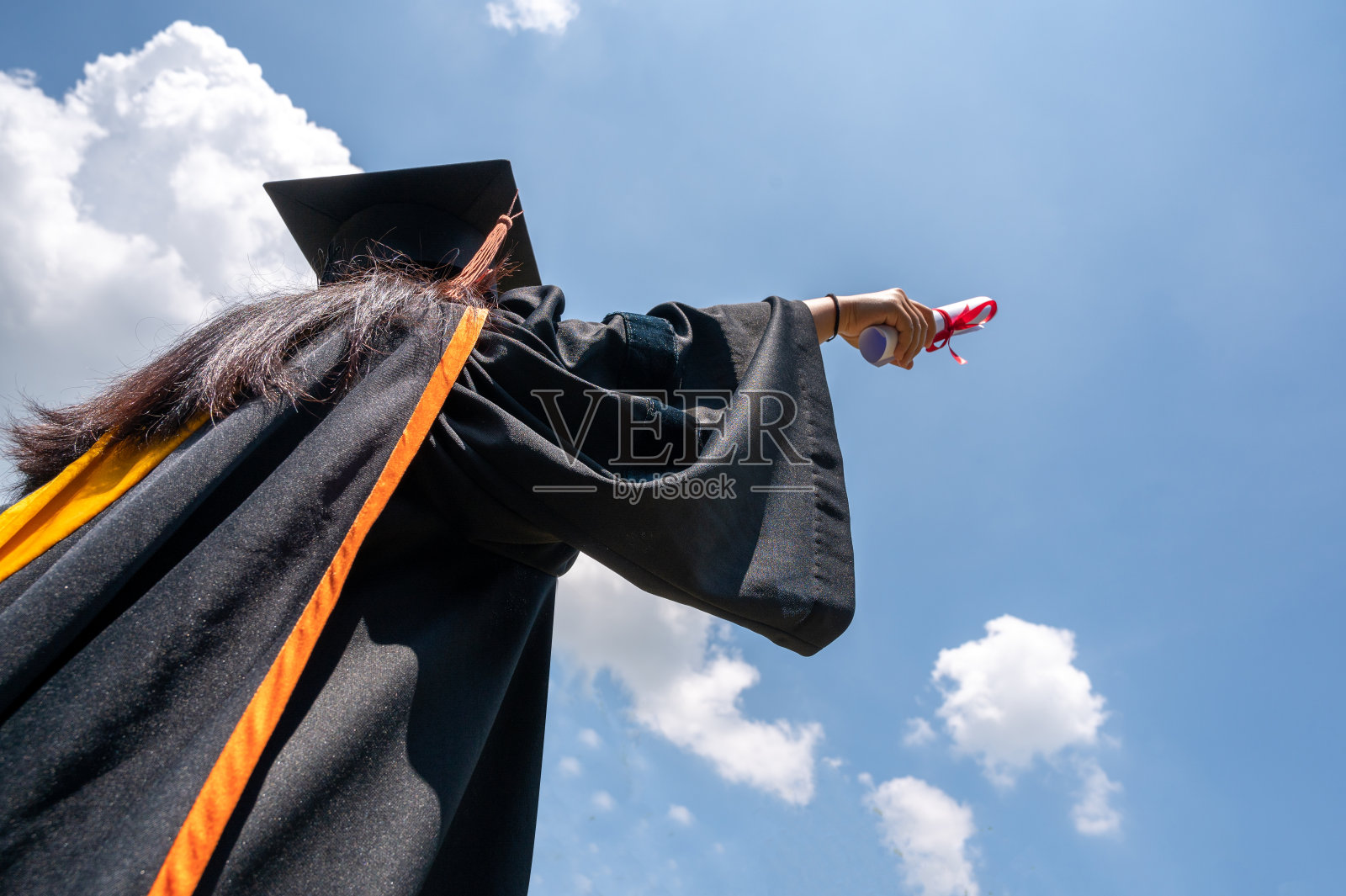 毕业生的黑色帽子漂浮在天空中。照片摄影图片