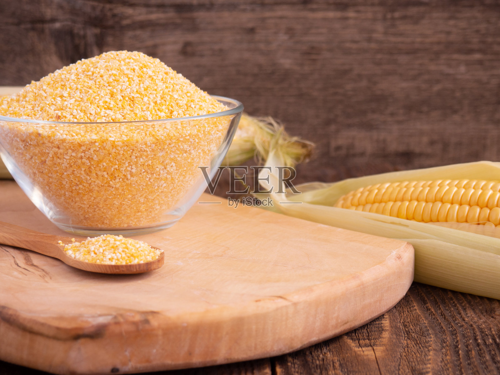 玻璃碗里的玉米糁和木勺特写在一张旧木桌上，复制空间照片摄影图片