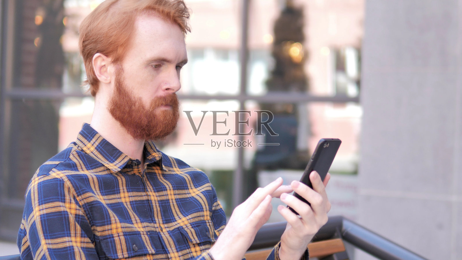 一名年轻人坐在户外使用智能手机照片摄影图片