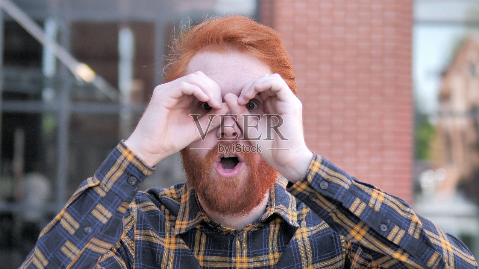 红发胡子年轻人的双眼手势照片摄影图片