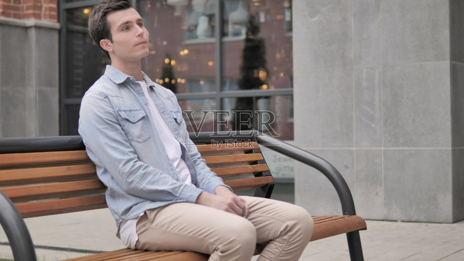 坐在长凳上等待的年轻人照片摄影图片