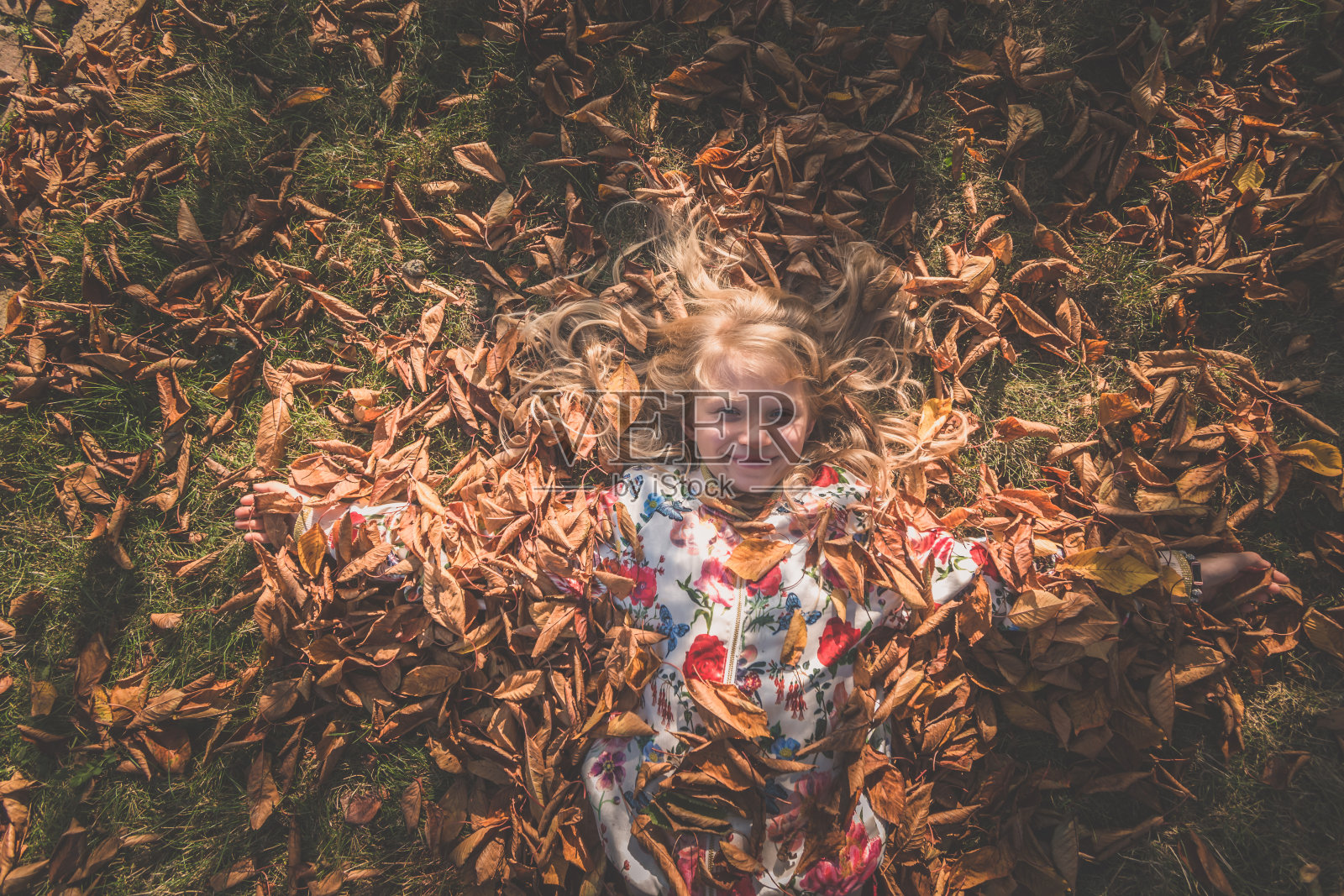 五彩缤纷的秋天和快乐的孩子躺在橙色，黄色的叶子照片摄影图片