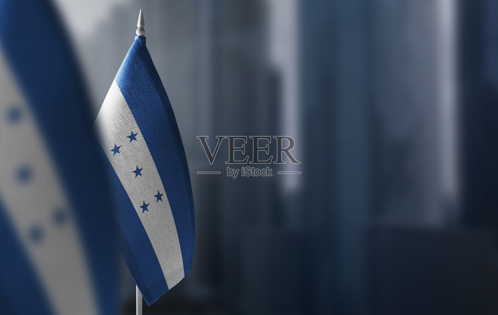 城市模糊的背景上挂着洪都拉斯的小国旗照片摄影图片