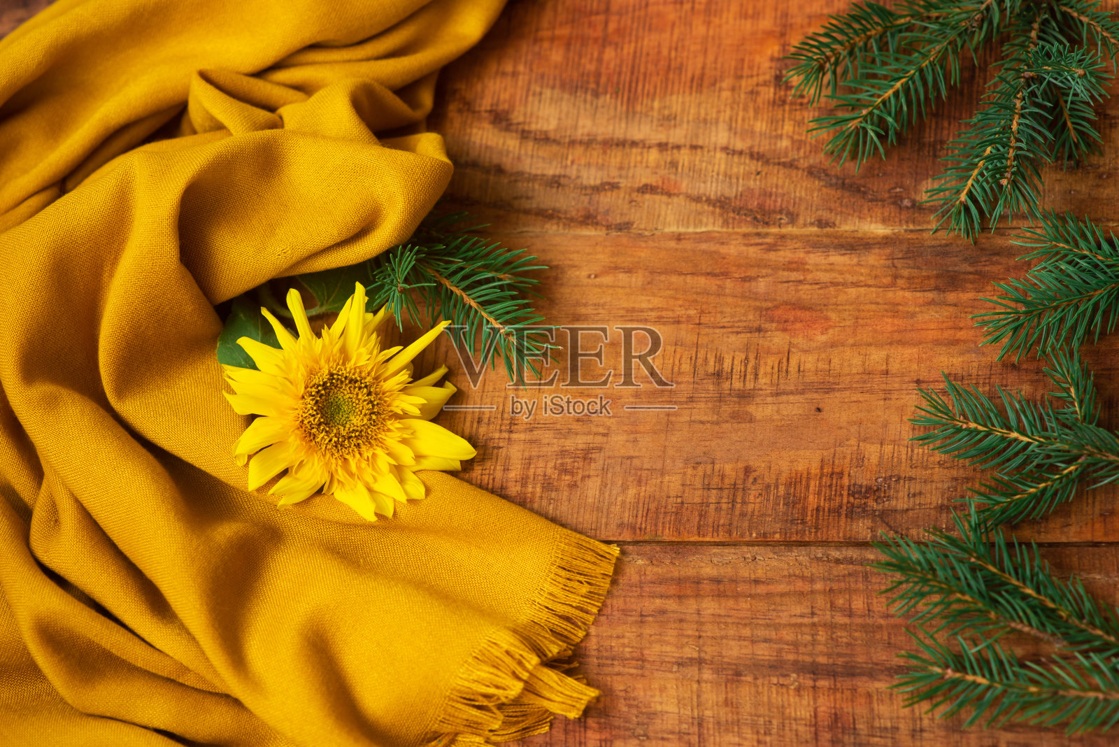 冬天,温暖的气氛。一幅以云杉树枝、黄色围巾和向日葵为背景的木制作品照片摄影图片