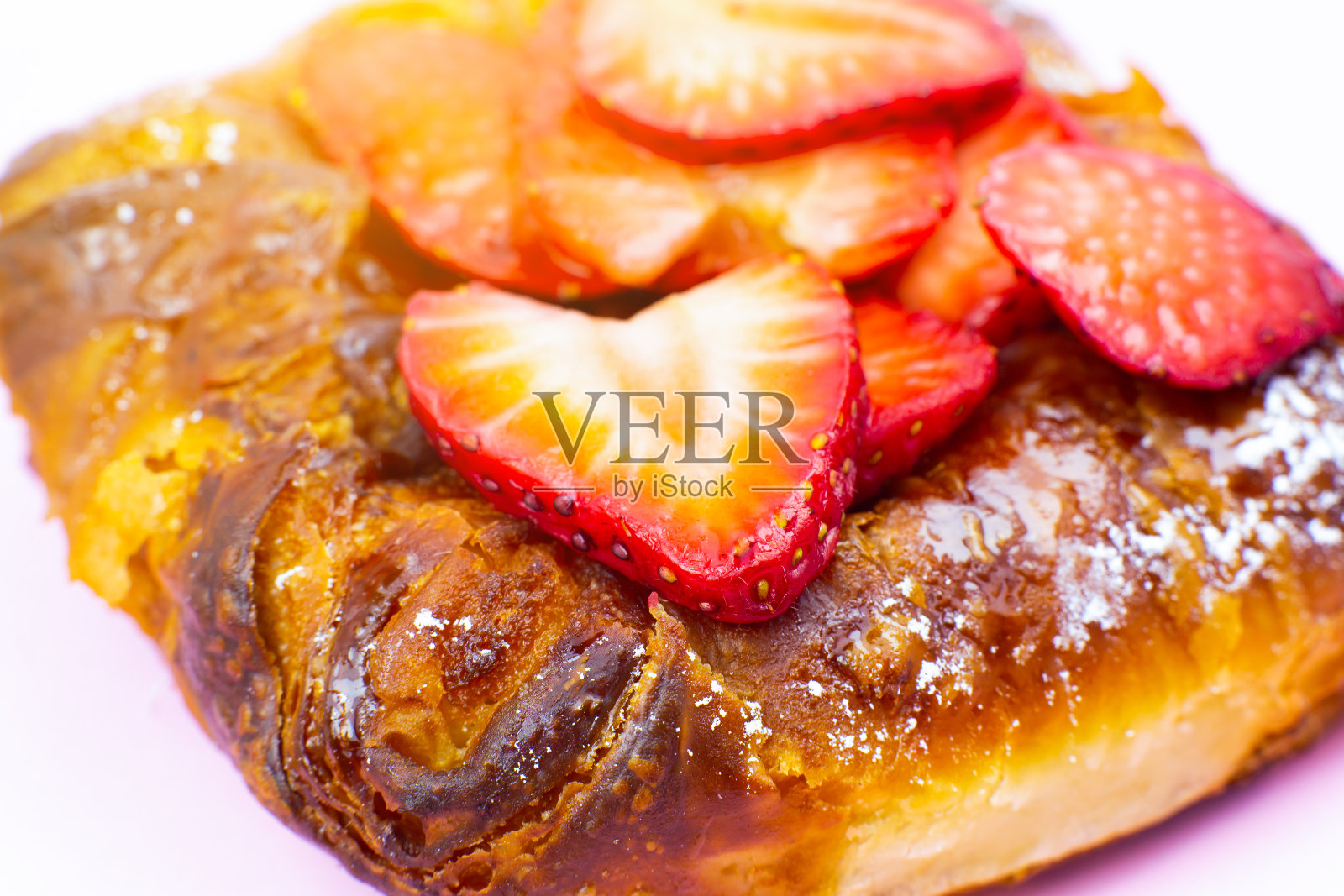 酥皮的小圆面包或卷。新鲜草莓蛋糕。美味的糖果诱惑和甜点在粉红色的背景。极简主义，原创和创意的形象。美丽的食物壁纸。照片摄影图片