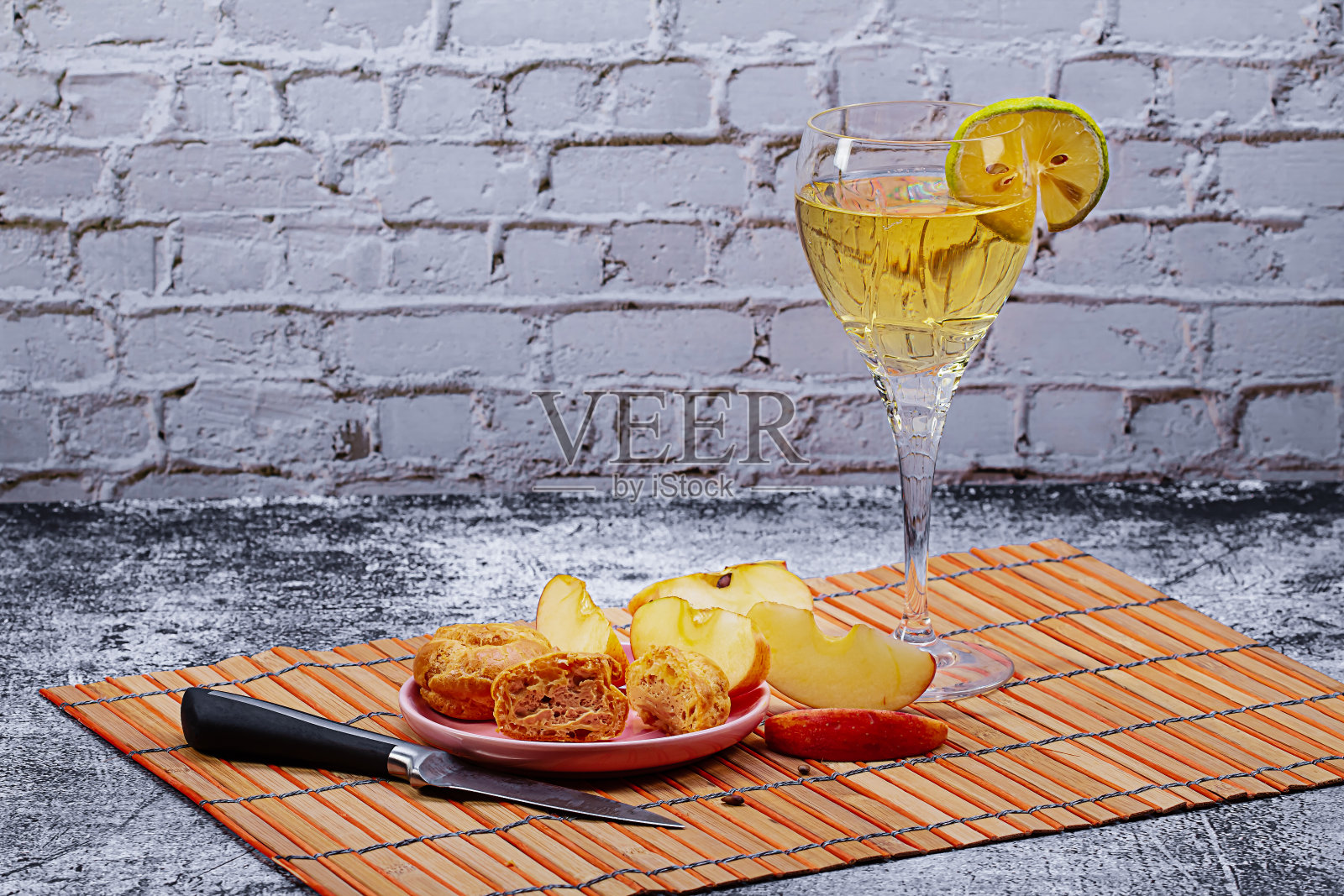一杯柠檬葡萄酒、一份闪电泡芙和厨房桌上的苹果片美食照片照片摄影图片