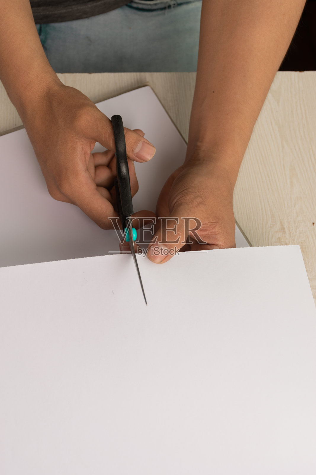 一个人的手在桌上用剪刀剪一张白纸的细节，工艺品、艺术和创造力的工作工具照片摄影图片