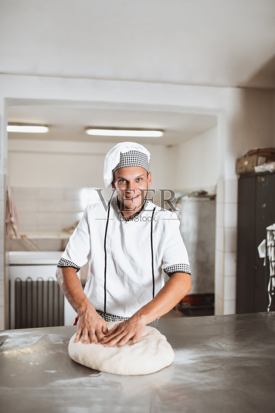 微笑的男面包师在面包房揉比萨饼面团照片摄影图片