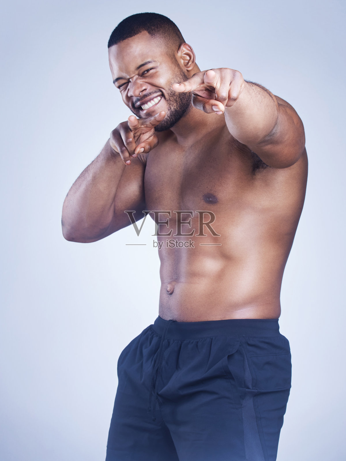 摄影棚拍摄的一个英俊的年轻男子指着灰色的背景照片摄影图片