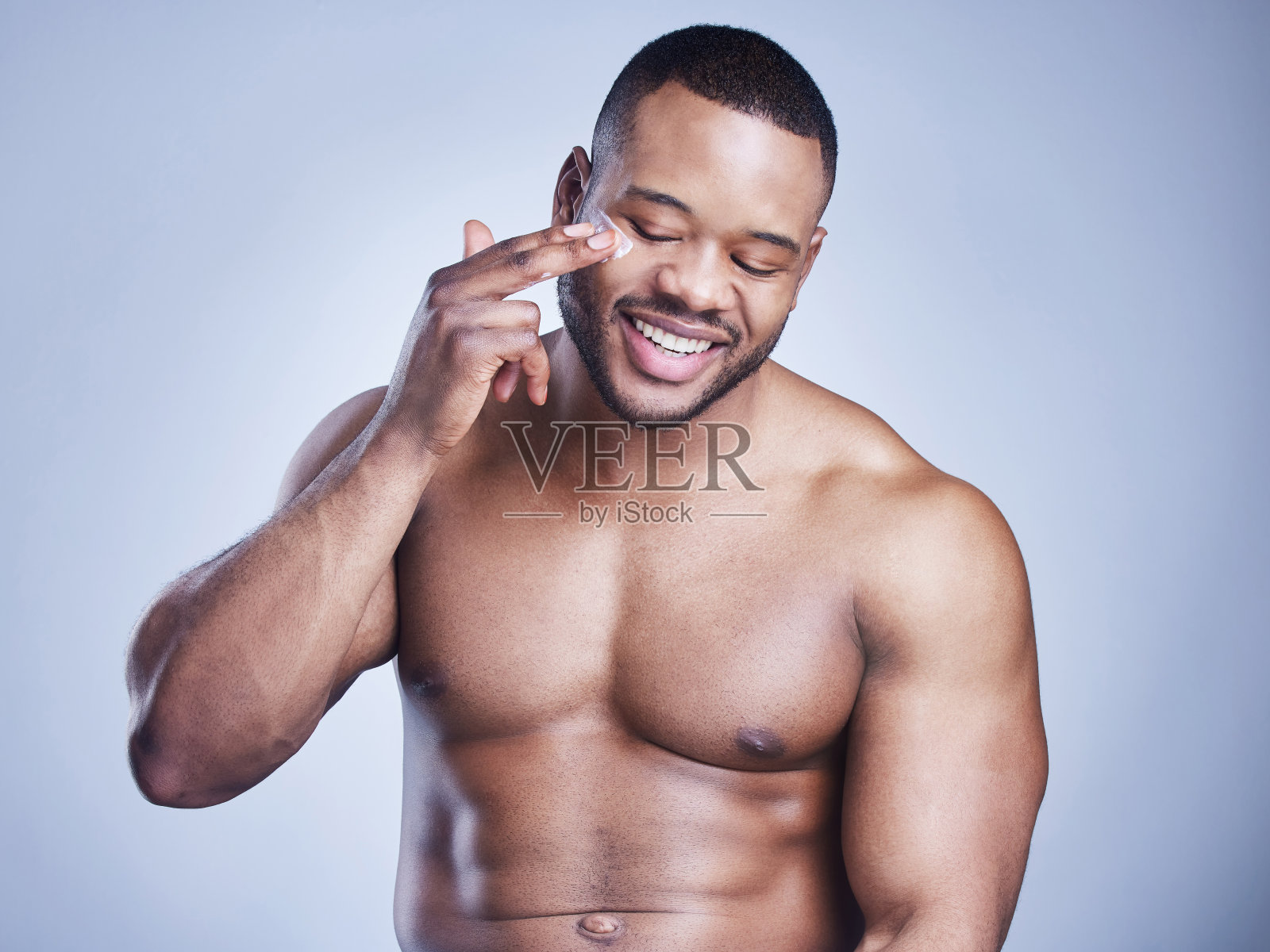 一名英俊的年轻男子在蓝色背景下涂抹润肤霜照片摄影图片