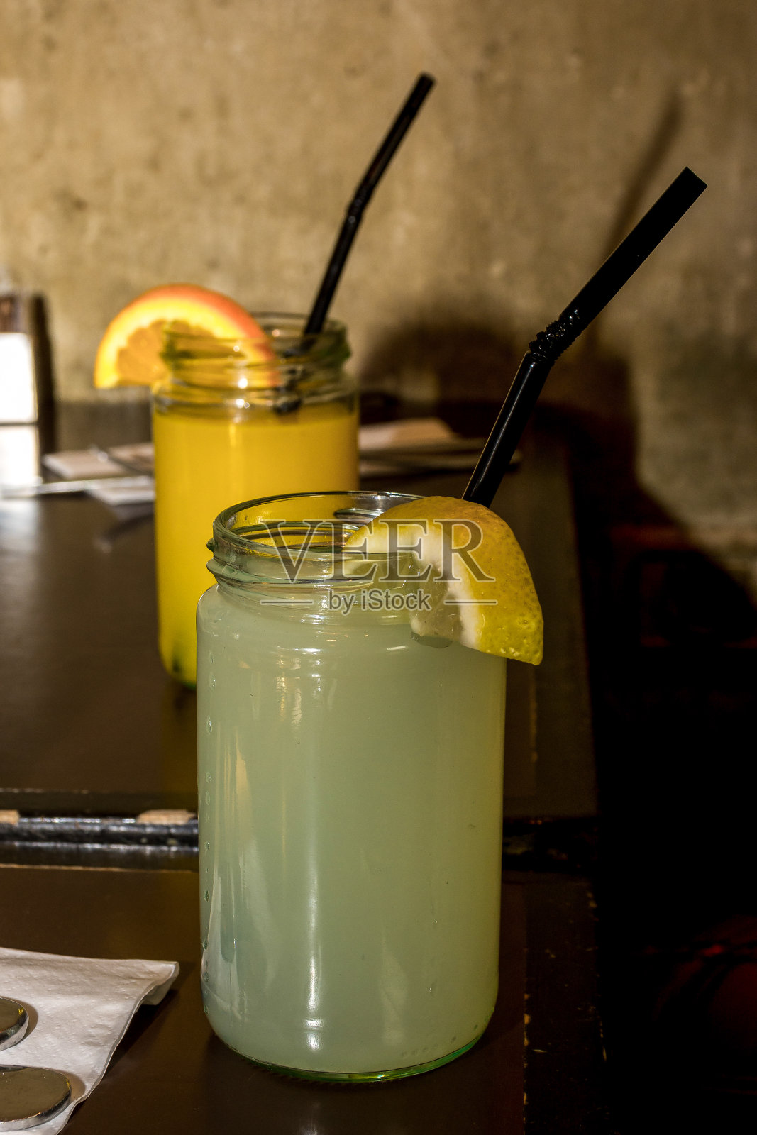 餐厅里装满柠檬水和橙汁的罐头瓶，配有水果片和吸管照片摄影图片