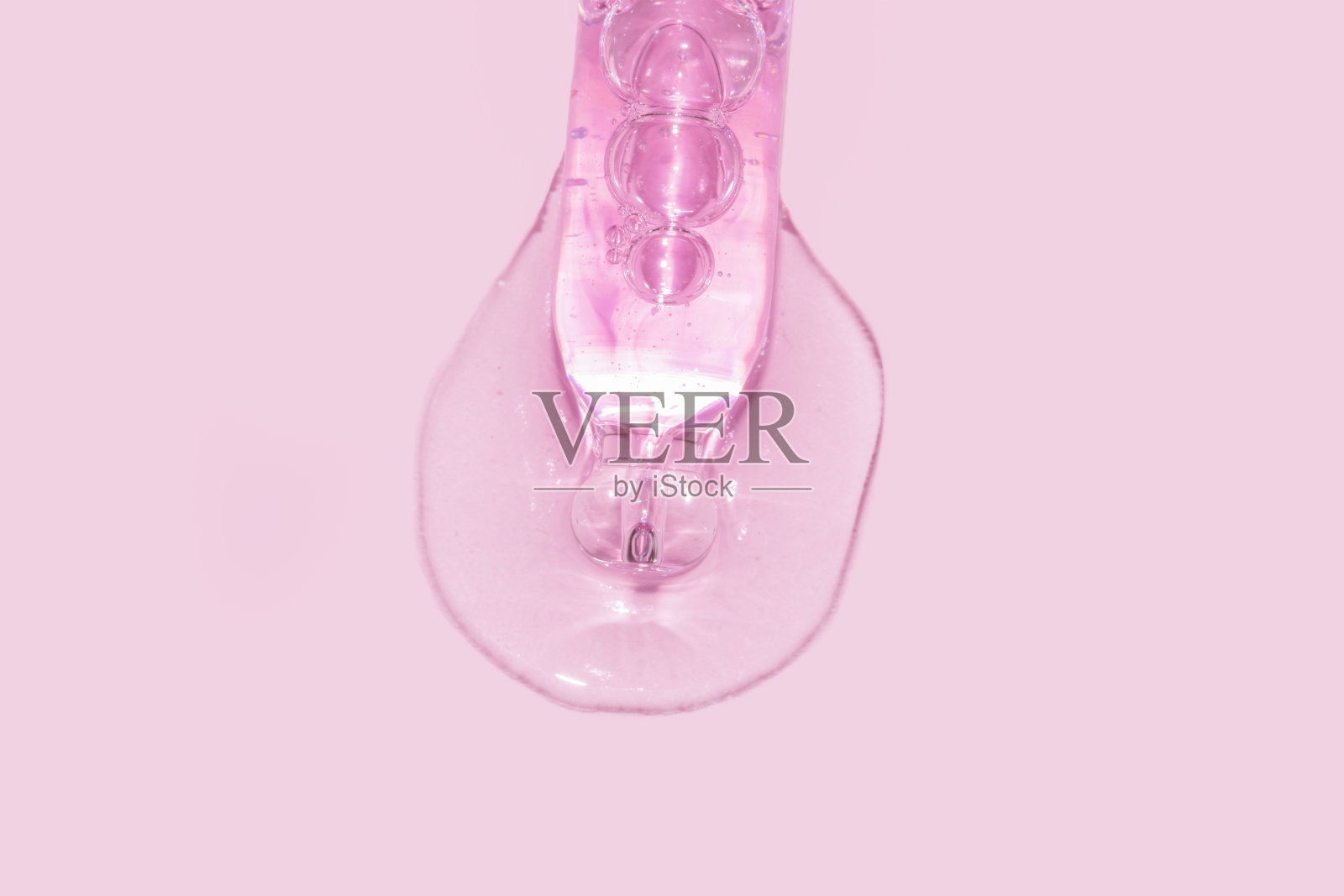 特写吸管滴管与倾倒面部血清在粉红色的背景照片摄影图片