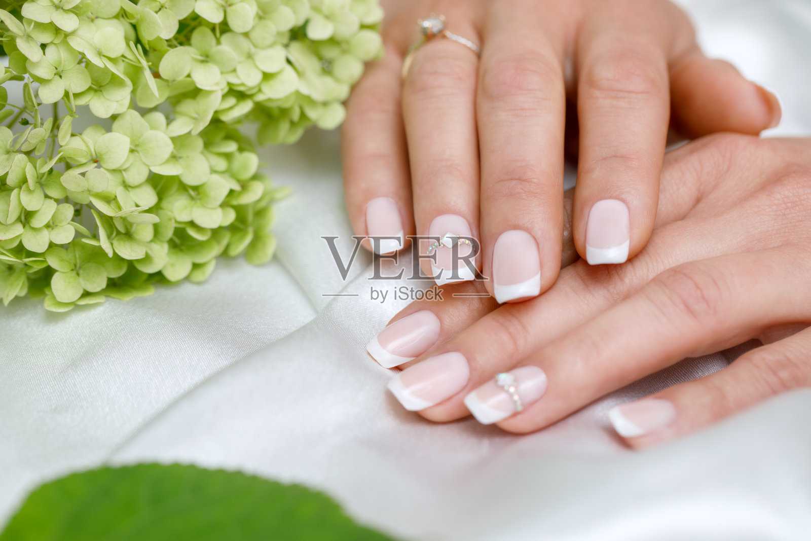 漂亮的粉色和白色的法式美甲配上莱茵石为新娘做的。特写指甲。婚礼配件照片摄影图片