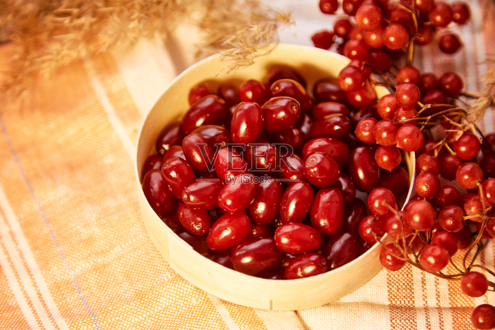 有机秋浆果荚蒾和山茱萸在木碗舒适的家内部。茶、果盘和果酱的健康食品概念。顶视图背景，复制空间照片摄影图片