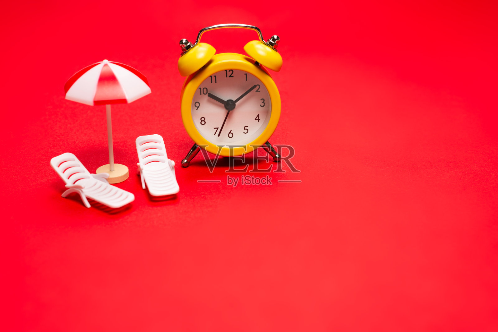 时间旅行。日光躺椅，雨伞和闹钟。照片摄影图片