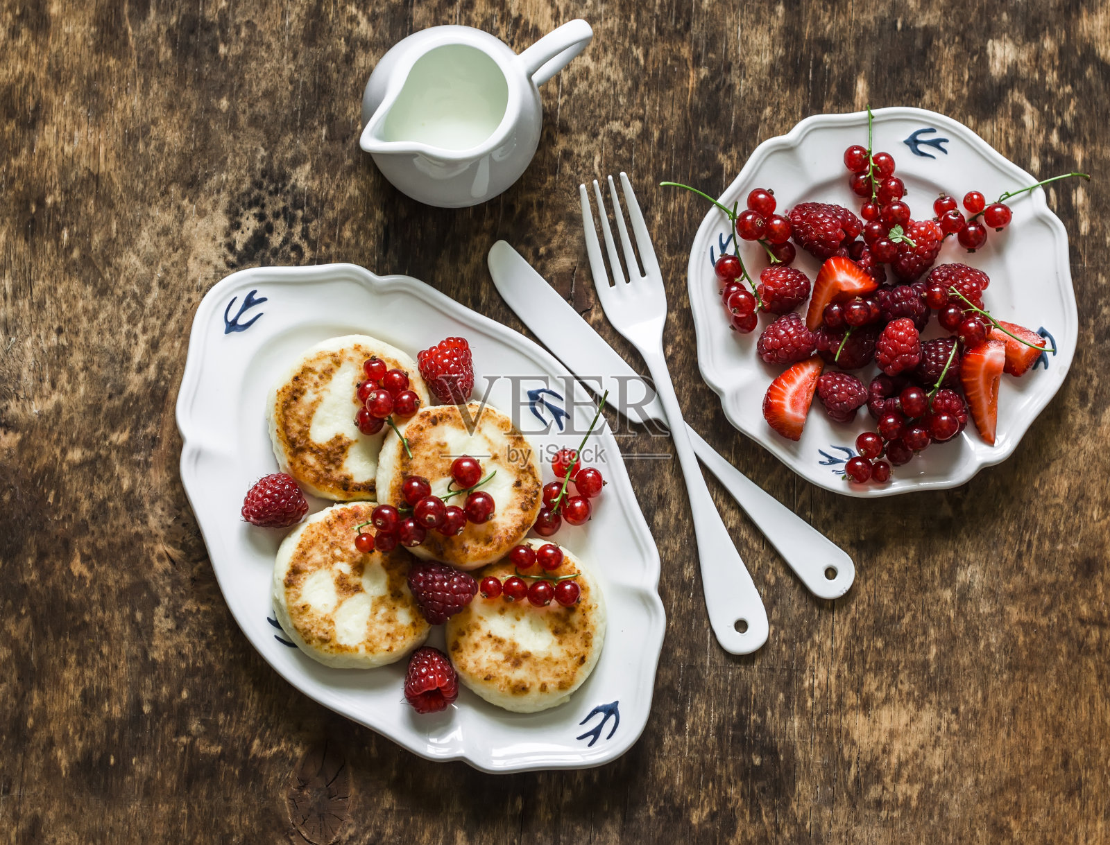 西尔尼基与红醋栗，覆盆子和酸奶油木制背景，俯视图。美味的早餐,早午餐照片摄影图片