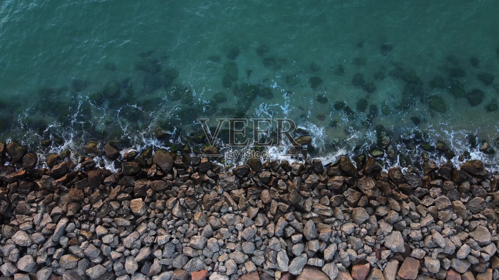 海岸上布满了石头，海浪拍打着岩石海岸。照片摄影图片