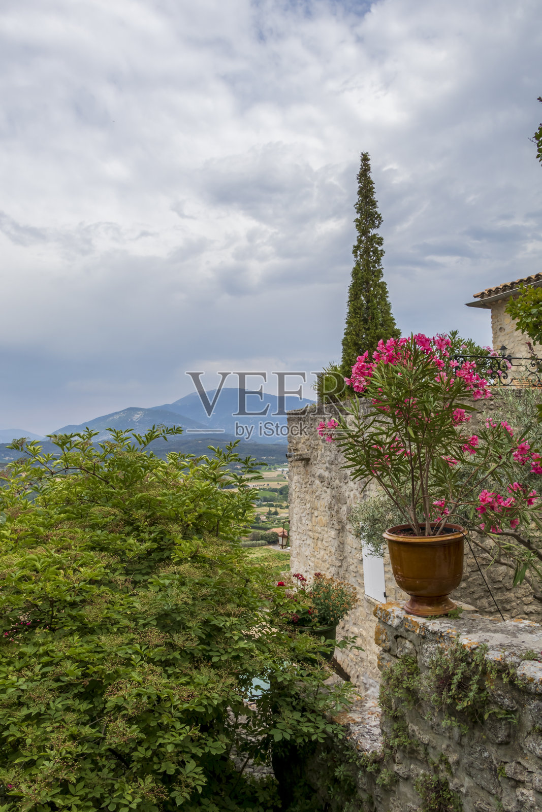 在法国普罗旺斯的沃克卢兹，典型的法国中世纪小村庄的阳台上的陶罐里有粉红色的花朵照片摄影图片