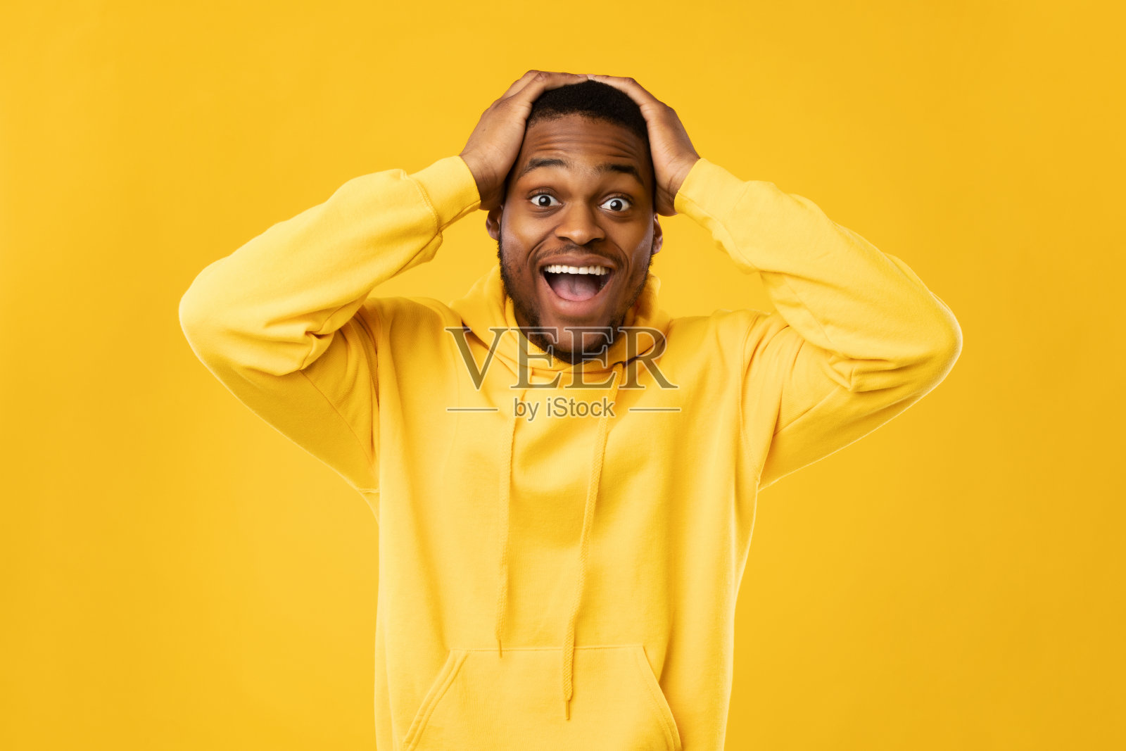 站在黄色背景上，兴奋的黑人喊着摸头照片摄影图片