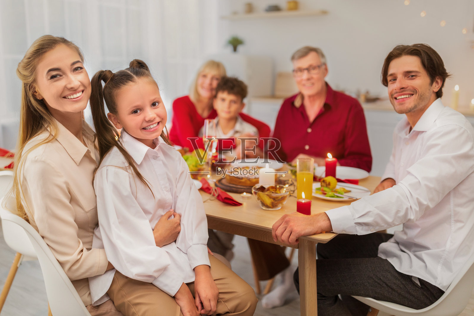 幸福的多代家庭坐在节日餐桌前，看着相机微笑照片摄影图片