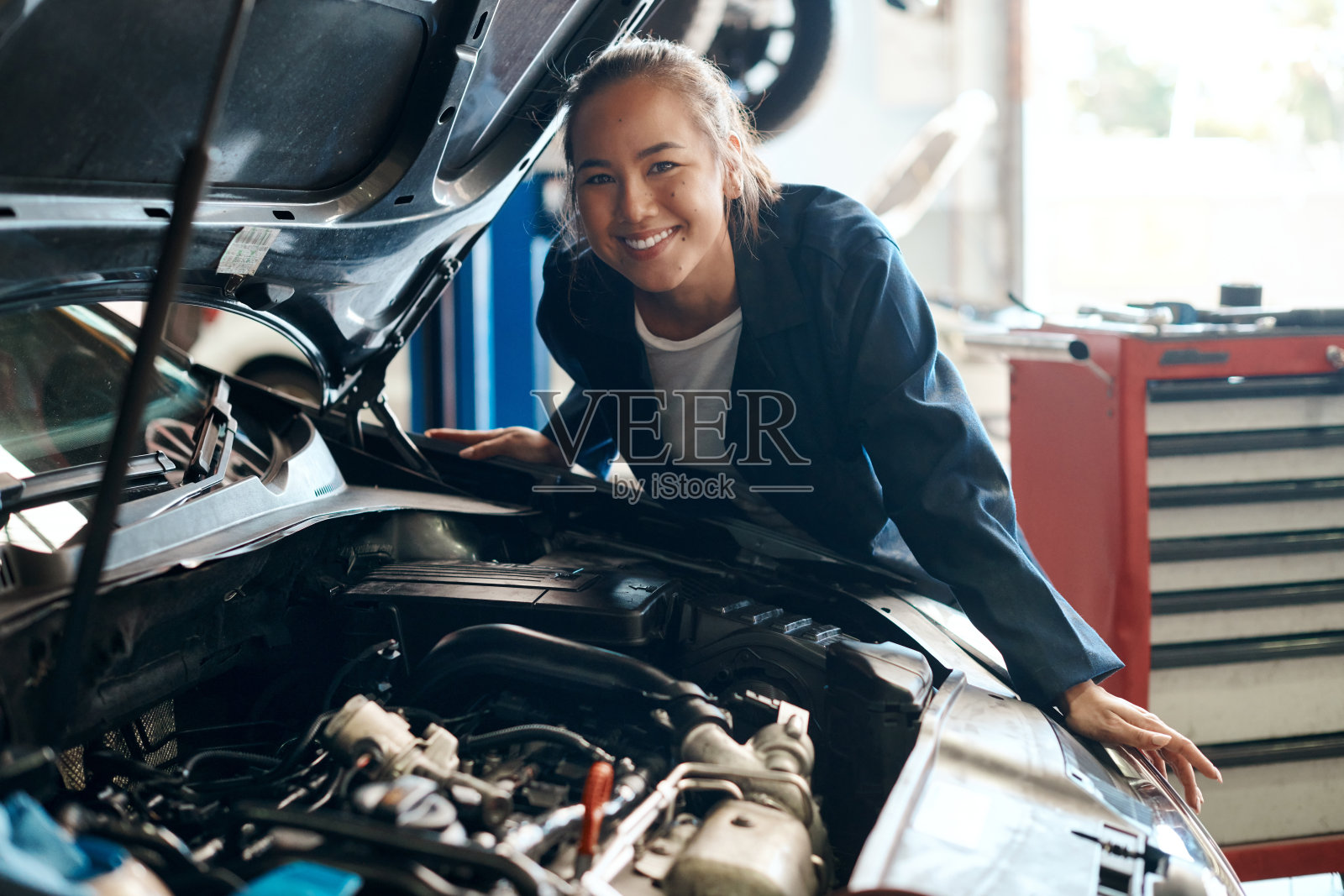 图为一名女机械师在汽车修理店修车照片摄影图片